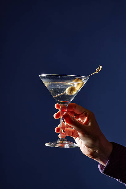 istock Holding Garnished Martini Glass With Olives Against Blue Background 2206816551