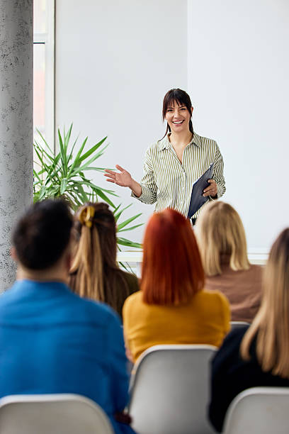 istock Smiling Woman Presenting to Audience in Modern Indoor Setting 2206817633