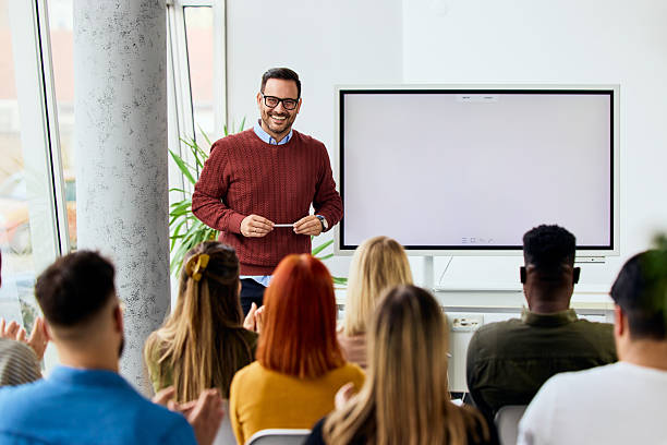 istock Smiling Professional Giving a Presentation to an Engaged Audience in a Workshop Setting 2206817637