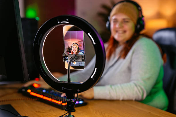 istock Young Woman Streaming On A Phone While Playing A Video Game On Her Desktop PC 2206818531