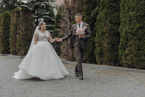 istock A bride and groom are walking down a street, holding hands 2206824642
