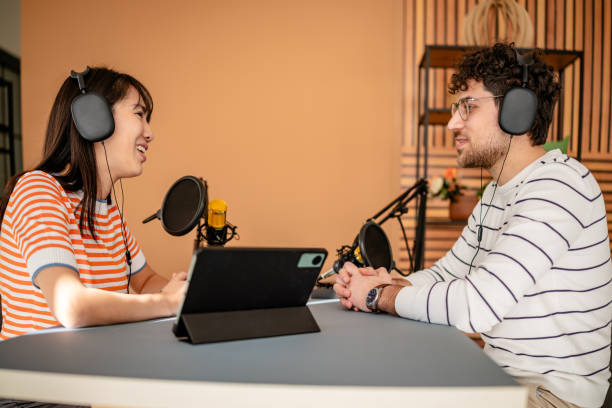istock Exciting podcast hosts engage in lively discussion at a modern recording studio with sound equipment and cheerful atmosphere 2206831692