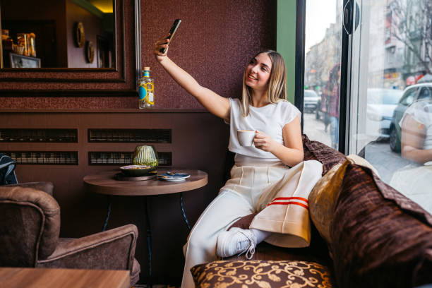istock Young Woman Taking Selfies Using Phone While Drinking Coffee In A Coffee Shop 2206834264