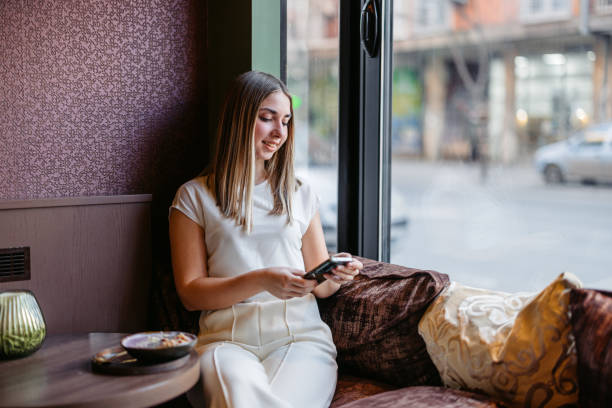 istock Young Woman Using A Phone In A Coffee Shop 2206834753