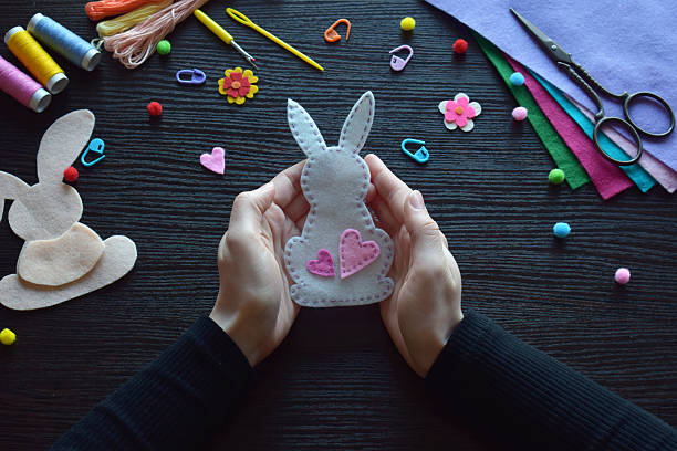 istock Displaying finished felt bunny ornament, Easter handmade decoration, DIY craft project, festive accessory, colorful workspace materials, spring holiday preparation, threads, buttons, creative process 2206836633
