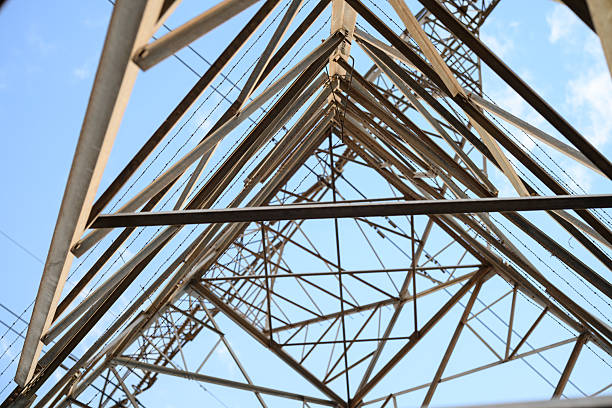 Electric pylons steel structures seen from underneath creating patterns and designs against blue sky
