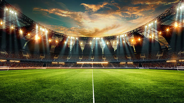 Wide-angle of modern football stadium with glass roof, bright stadium lights illuminating green field against cloudy sunset sky above. 3D render. Wide-angle of modern football stadium with glass roof, bright stadium lights illuminating green field against cloudy sunset sky above. 3D render. Concept of sport event, championship, game. soccer field stock pictures, royalty-free photos & images