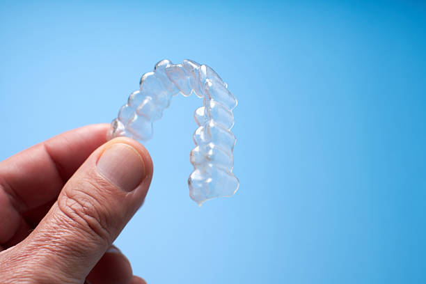 istock Clear Dental Aligner Held in Hand Against Blue Background 2206836774