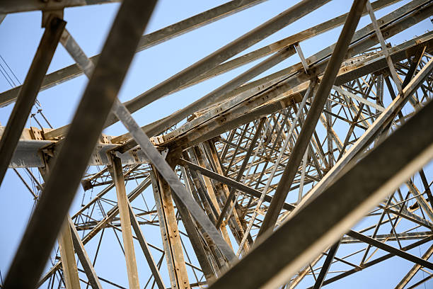 Electric pylons steel structures seen from underneath creating patterns and designs against blue sky
