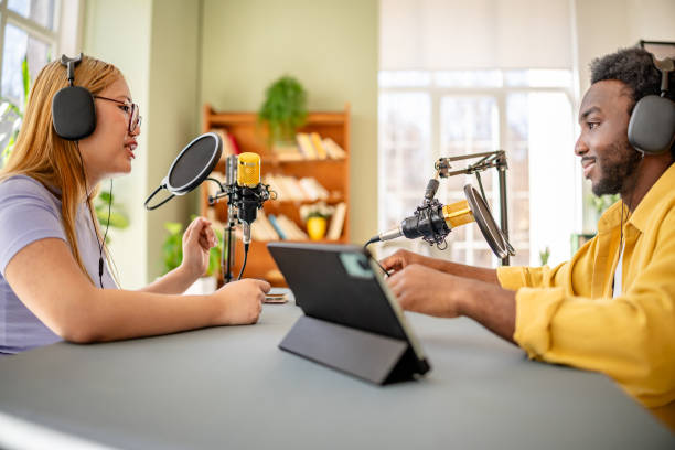 istock Two young adults engaged in a lively podcast discussion in a modern studio setting, showcasing teamwork and vibrant communication 2206836980
