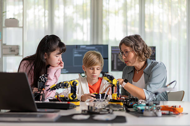 istock Young students in a futuristic classroom engage in hands-on STEM learning, experimenting with robotic arms using Bluetooth gloves. This interactive session fosters curiosity, creativity, and innovation while enhancing skills in artificial intelligence, co 2206837545