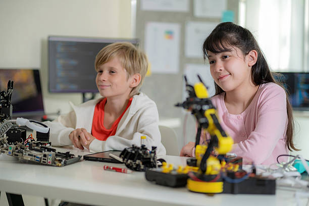 istock Two elementary school children engage in a hands-on robotics experiment, moving their hands in smart gloves to control a robotic arm. This interactive learning activity encourages innovation, curiosity, and technical expertise, fostering skills in AI 2206837618
