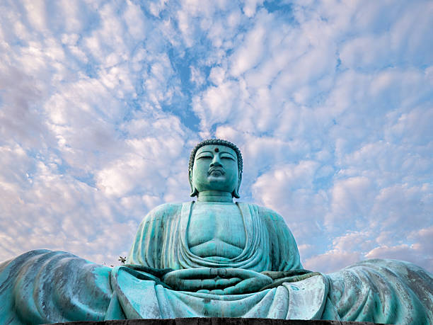 An ant's eye view of the Daibutsu Buddha at Wat Phra That Doi Pra Chan, Lampang. This low angle shot emphasizes the Buddha's size against the vast sky, creating a sense of awe and peaceThe majestic copper-green Daibutsu Buddha stands beneath the pre-dawn blue sky at Wat Phra That Doi Phra Chan, reflecting peace, faith, and the beauty of Buddhism at sunriseAn ant's eye view from the right side of the copper-green Daibutsu Buddha at Wat Phra That Doi Phra Chan reveals the statue's grandeur beneath the pre-dawn blue sky, conveying faith and reverenceLow-angle (ant's eye view) shot from the left side of the copper-green Daibutsu Buddha at Wat Phra That Doi Phra Chan showcases the statue's imposing presence against the pre-dawn blue sky, conveying faith and reverence