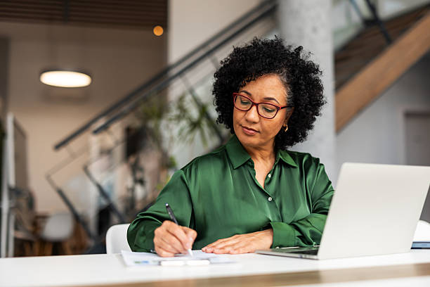 istock Focused Professional Woman Writing Notes at Modern Office Desk 2206841545