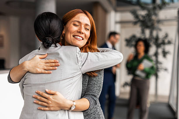Two Happy Businesswomen Hugging in Modern Office Environment