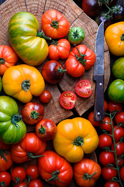 istock Ripe tomatoes different kind and colors on wooden cutting board 2206841977