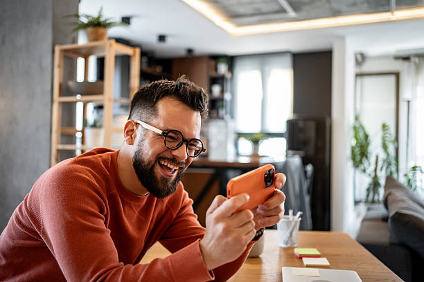 istock Happy freelancer playing mobile games at home office desk 2206852019