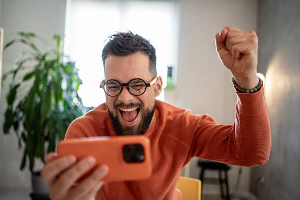 istock Excited man celebrating success while using smartphone at home 2206852133