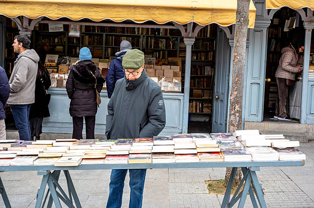 Views of the historic book stalls in Madrid, Spain.  Next to the Botanic Gardens lies a small pedestrian street called Cuesta de Moyano.  this street contains 30 book stalls which are open every day of the week and date back to 1925.  The stalls are now run by the children and grandchildren of the book fair's founders.  The books offered range from philosophy, literature, art , essays, antique comic books, and out of print volumes.