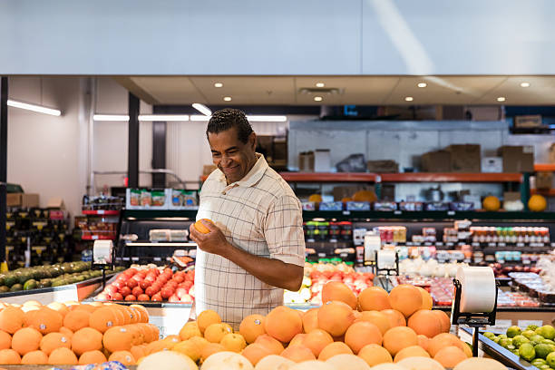 istock Smiling Man Choosing Oranges at Grocery Store 2206856166