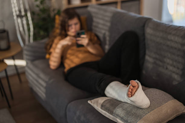 istock Girl resting injured leg and using phone 2206858340