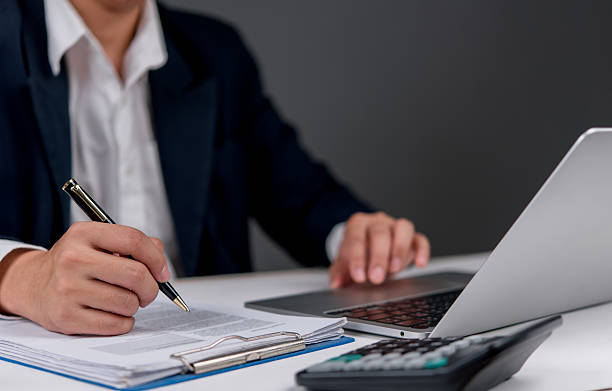 istock businessman working on papers, taking notes, and analyzing financial data on his laptop. 2206859617