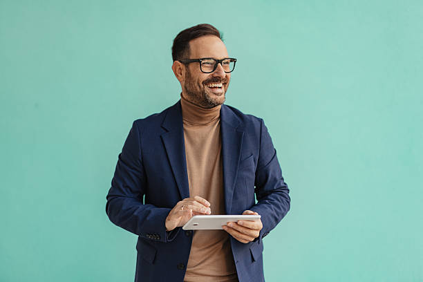 istock Happy man with tablet smiling against turquoise wall 2206861425