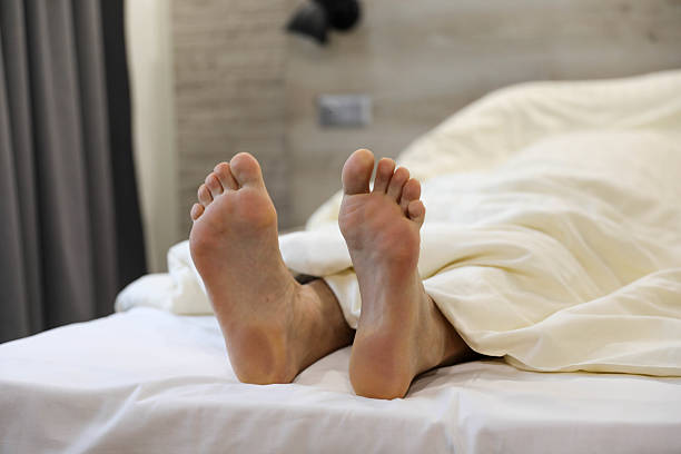 istock Sleeping In: Cozy Feet Partially Covered with a Blanket 2206862082