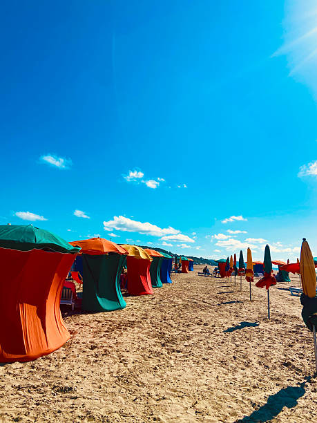 istock Orange and green cabanas on beach with umbrellas and clear sky 2206865695