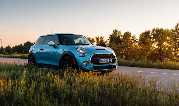 Three quarter front view of british compact hatchback on a road in rural area in rays of setting sun. Ukraine - September 11 2021.