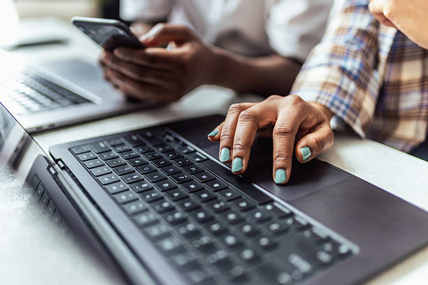 istock Close-Up of Hands Typing on Laptop Keyboard Next to Collegue using Smartphone 2206868185