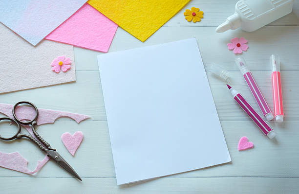 istock Creative flat lay composition of DIY greeting card crafting materials, including colorful felt flowers, scissors, glue, and blank paper, arranged on a white wooden background, showcasing the process of making a personalized handmade card 2206868824