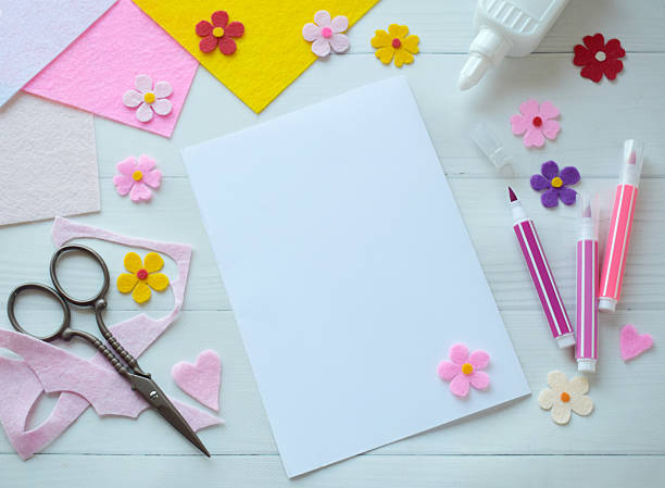 istock Creative flat lay composition of DIY greeting card crafting materials, including colorful felt flowers, scissors, glue, and blank paper, arranged on a white wooden background, showcasing the process of making a personalized handmade card 2206868861