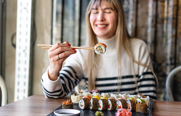 istock Woman eating sushi rolls with chopsticks 2206869635