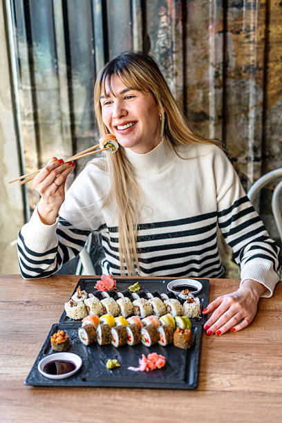 istock Woman eating sushi rolls with chopsticks 2206869673