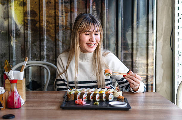 istock Woman eating sushi rolls with chopsticks 2206870218