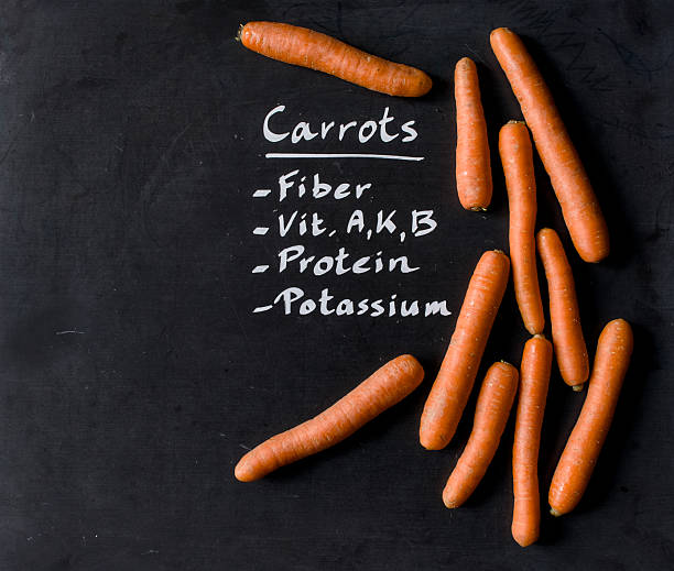 Carrots for a well balanced diet arranged on black chalkboard - vegetables with nutrition facts written on black chalkboard - healthy eating, nutrition facts, copy space