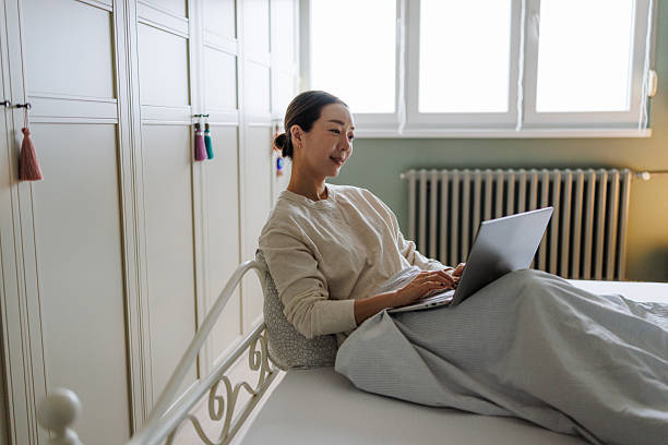 Woman relaxing with a laptop in a cozy bedroom setting