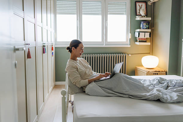 istock Woman using a laptop while relaxing in a cozy bedroom 2206870909