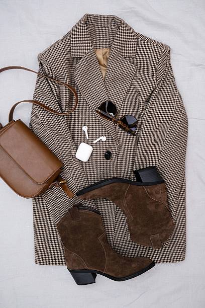 istock This stylish fall ensemble features a chic brown blazer, trendy ankle boots, headphones and a fashionable dark brown handbag. 2206871122