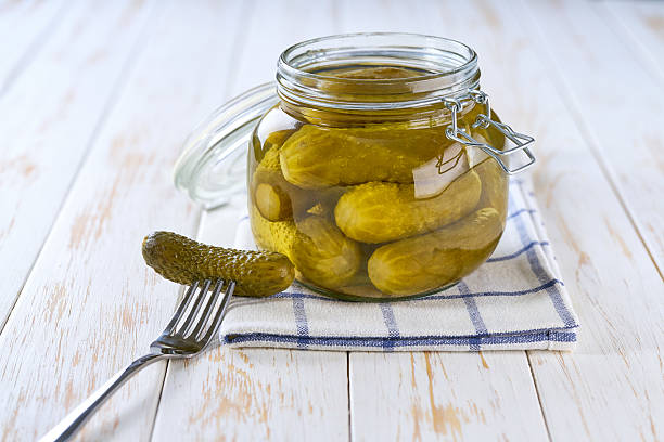 istock pickled cucumbers in a jar on a white wooden table, selective focus. 2206872335
