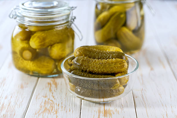 istock pickled cucumbers in a transparent glass bowl on a white wooden table, selective focus. 2206872986