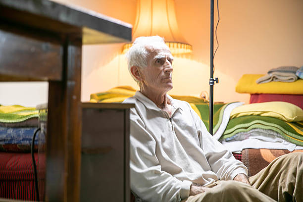 Portrait of an 80+ year old man sitting on the floor of his room.
