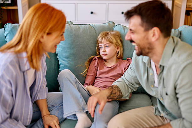 istock Sad daughter lying on sofa while parents are trying to make her laugh 2206876458