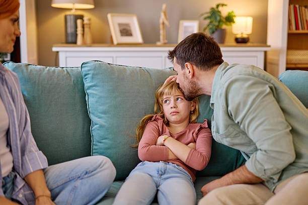 istock Father comforting sad daughter at home with mother sitting next to them 2206876481