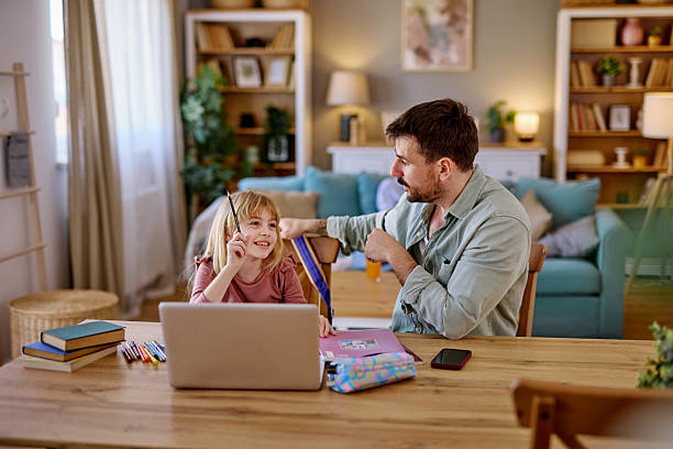istock Father helping daughter with homework using laptop at home 2206877146