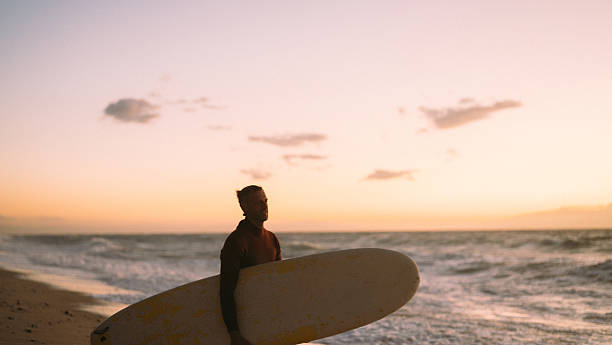 istock Male surfer holding his surfboard at the beach 2206879266