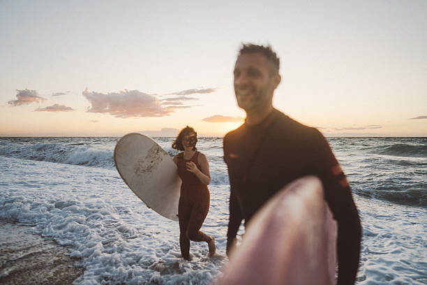 Photo of a heterosexual couple of surfers at the beach