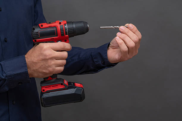 istock A man inserts a drill bit into a cordless screwdriver. on a grey background 2206881693