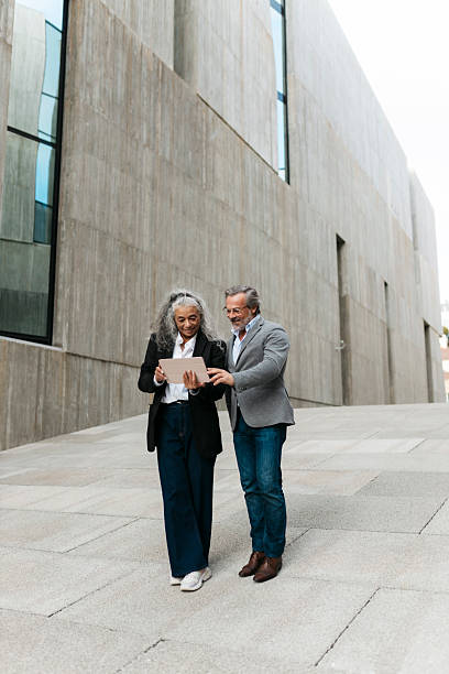 istock Smiling senior businesspeople using digital tablet outside office building 2206881774